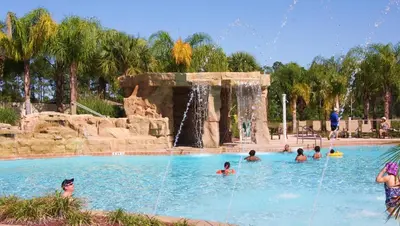a group of people in a swimming pool with a waterfall at Family 4-Bedroom Pool Home Near Disney World in Kissimmee