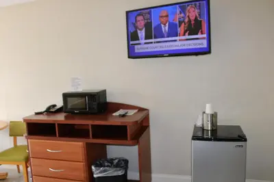 a tv hanging on a wall above a desk with a microwave at Magic Key - Near Disney in Kissimmee