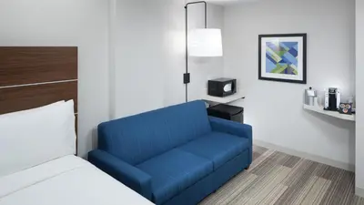 a blue chair in a room with a bed at Holiday Inn Express & Suites Orlando At SeaWorld by IHG - With Free Shuttle Service to SeaWorld Parks in Orlando