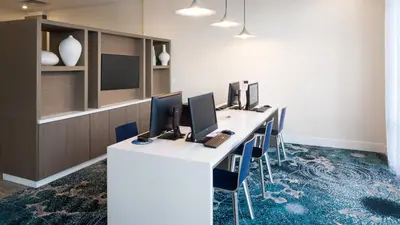 an office with a long desk with four computers on it at Holiday Inn Express & Suites Orlando At SeaWorld by IHG - With Free Shuttle Service to SeaWorld Parks in Orlando