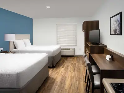 a hotel room with two beds and a desk at Extended Stay America Select Suites - Orlando - Airport in Orlando