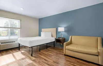 a bedroom with a bed and a couch and a chair at Extended Stay America Select Suites - Orlando - Airport in Orlando