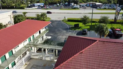 a building with a red roof and a parking lot at Riviera Motel in Kissimmee