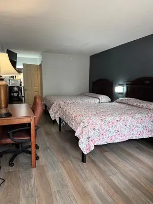 a room with two beds and a desk and a table at Riviera Motel in Kissimmee