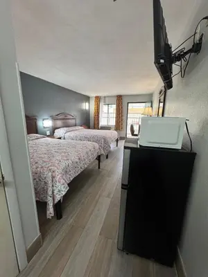 a hotel room with two beds and a flat screen tv at Riviera Motel in Kissimmee
