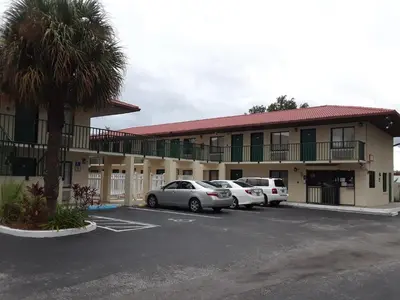 a hotel with cars parked in a parking lot at Riviera Motel in Kissimmee