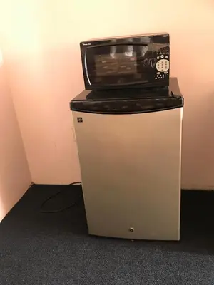 a microwave sitting on top of a small refrigerator at Enterprise Motel in Kissimmee