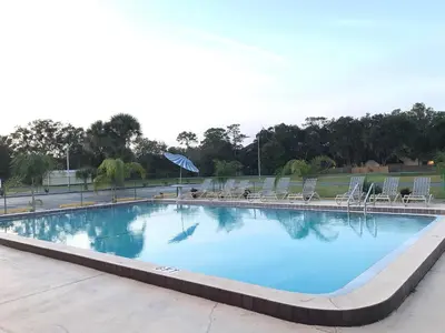 a large swimming pool with chairs and blue water at Enterprise Motel in Kissimmee