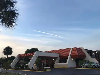 a building with a car parked in front of it at Enterprise Motel in Kissimmee