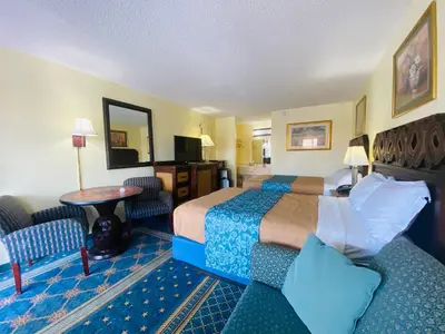 a hotel room with two beds and a table and chairs at Maple Leaf Inn & Suites in Kissimmee