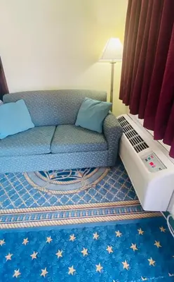 a living room with a couch and a air conditioner at Maple Leaf Inn & Suites in Kissimmee