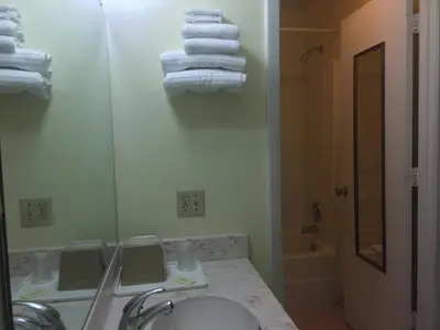 a bathroom with a sink and a mirror and towels at Maple Leaf Inn & Suites in Kissimmee