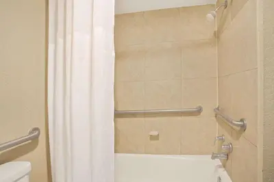 a bathroom with a shower curtain and a toilet at Days Inn by Wyndham Orlando Airport Florida Mall in Orlando