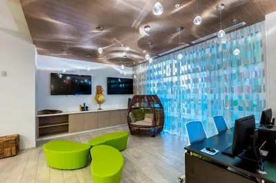 an office with green chairs and a desk and a tv at TownePlace Suites by Marriott Orlando at SeaWorld in Orlando
