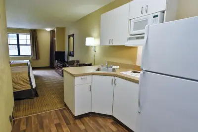 a kitchen with a white refrigerator and a room at Extended Stay America Select Suites - Orlando - Conven Ctr - Sports Complex in Orlando
