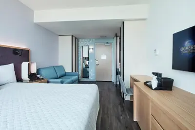 a hotel room with a bed and a desk and a television at Universal's Aventura Hotel in Orlando