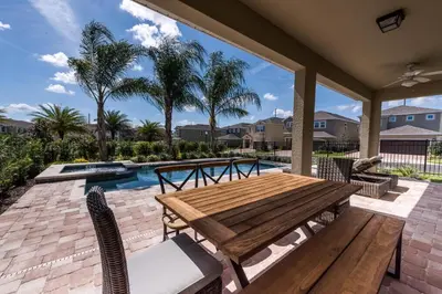 a patio with a wooden table and chairs and a pool at Luxury Home Near Disney With Private Pool, Waterpark & Resort Access At Encore Resorts Reunion - 211Mn in Kissimmee