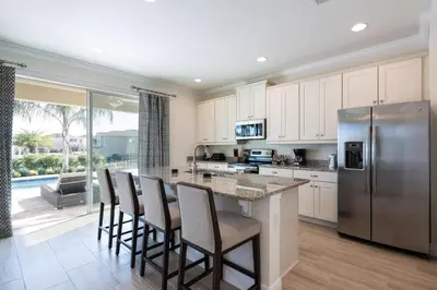 a kitchen with a bar with chairs and a refrigerator at Luxury Home Near Disney With Private Pool, Waterpark & Resort Access At Encore Resorts Reunion - 211Mn in Kissimmee