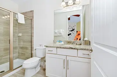 a white bathroom with a toilet and a shower at Luxury Home With Themed Rooms, Game Room And Waterpark & Resort Access Near Disney At Encore Resorts Reunion - 260Cl in Kissimmee