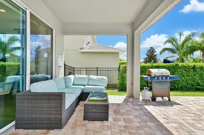 a patio with a couch and a grill on a patio at Luxury Home With Themed Rooms, Game Room And Waterpark & Resort Access Near Disney At Encore Resorts Reunion - 260Cl in Kissimmee
