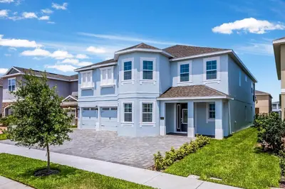 a large blue house with a driveway at Vibrant Elite Home With Theater Room And Waterpark & Resort Access Near Disney At Encore Resort - 7603Mc in Orlando