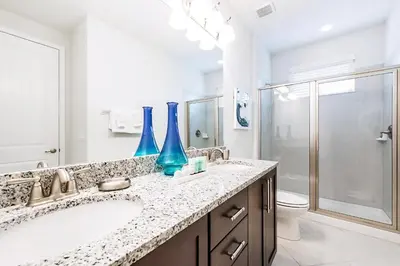 a bathroom with two sinks and a shower with blue vases at Vibrant Elite Home With Theater Room And Waterpark & Resort Access Near Disney At Encore Resort - 7603Mc in Orlando