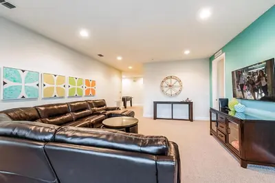 a living room with a leather couch and a television at Vibrant Elite Home With Theater Room And Waterpark & Resort Access Near Disney At Encore Resort - 7603Mc in Orlando