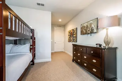 a bedroom with a bed and a dresser with a lamp at Vibrant Elite Home With Theater Room And Waterpark & Resort Access Near Disney At Encore Resort - 7603Mc in Orlando