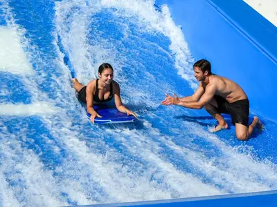 a man and woman riding a wave ride at a water park at Holiday Inn Resort Orlando Suites - Waterpark by IHG in Orlando
