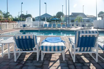 two chairs and a table in front of a pool at Villas at Fortune Place in Kissimmee