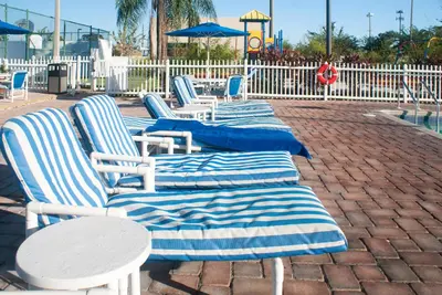 a row of blue and white lounge chairs and tables at Villas at Fortune Place in Kissimmee