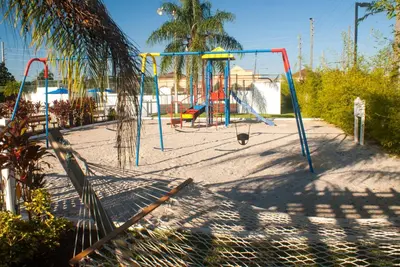 a playground with a swing set in the sand at Villas at Fortune Place in Kissimmee