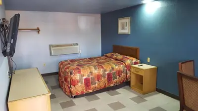 a hotel room with a bed and a fan at Budget Motel in Orlando
