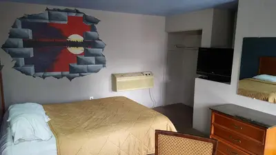 a small bedroom with a bed and a mirror at Budget Motel in Orlando