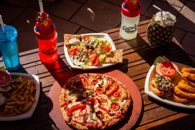 a table with plates of food and a pizza and french fries at Coco Key Hotel & Water Park Resort in Orlando