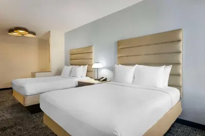 two beds in a hotel room with white pillows at Best Western Plus Universal Inn - Free Shuttle to Universal Studios! in Orlando