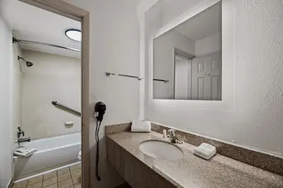 a bathroom with a sink and a mirror and a tub at Americas Best Value Inn Orlando, FL in Orlando