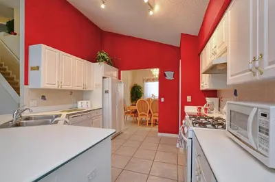 a kitchen with red walls and white appliances at Mickey's Lake Villa in Orlando