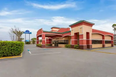 a large red building with a parking lot at Baymont by Wyndham Orlando North Millenia in Orlando