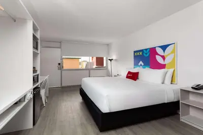 a white bedroom with a large bed and a tv at Baymont by Wyndham Orlando North Millenia in Orlando
