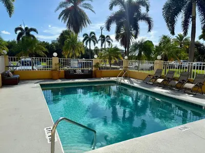 a swimming pool with chairs and palm trees at La Quinta by Wyndham Orlando Universal area - Free Shuttle to Universal in Orlando
