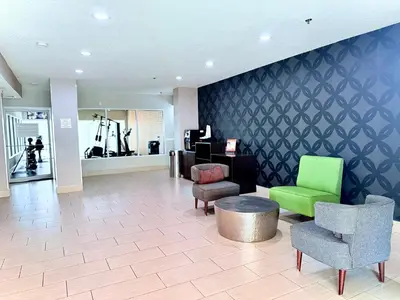a lobby with chairs and a table and a gym at La Quinta by Wyndham Orlando Universal area - Free Shuttle to Universal in Orlando