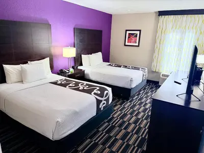 a hotel room with two beds and a flat screen tv at La Quinta by Wyndham Orlando Universal area - Free Shuttle to Universal in Orlando
