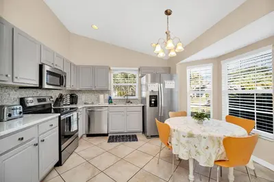 a kitchen with white cabinets and a table with chairs at Indian Creek 3.5 miles from Disney in Orlando