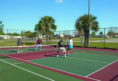 a group of people playing tennis on a tennis court at Orlando RV Resort in Orlando