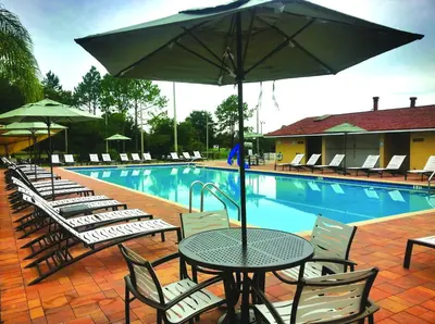 a table and chairs with an umbrella next to a swimming pool at Orlando RV Resort in Orlando