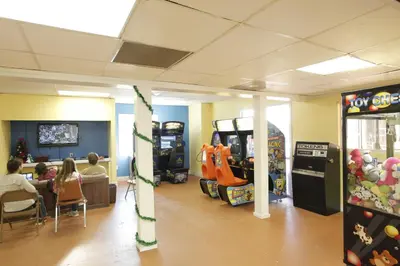 a restaurant with people sitting at a table and two video games at Orlando RV Resort in Orlando