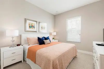 a bedroom with a bed with an orange blanket and a window at Summerville Vacation Resort in Orlando