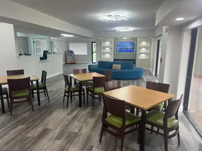 a waiting room with tables and chairs and a couch at Quality Inn & Suites Orlando East - UCF Area in Orlando