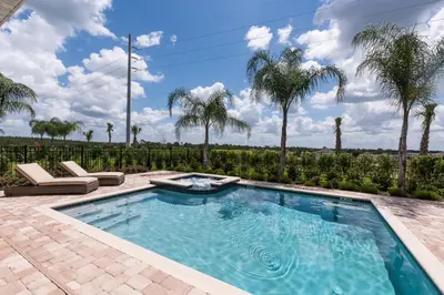 a swimming pool with palm trees in the background at Luxury Disney Dreams Home with Pool, Spa & Game Room in Orlando